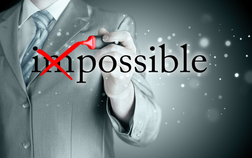 Businessman Hand turning the word Impossible into Possible with red marker