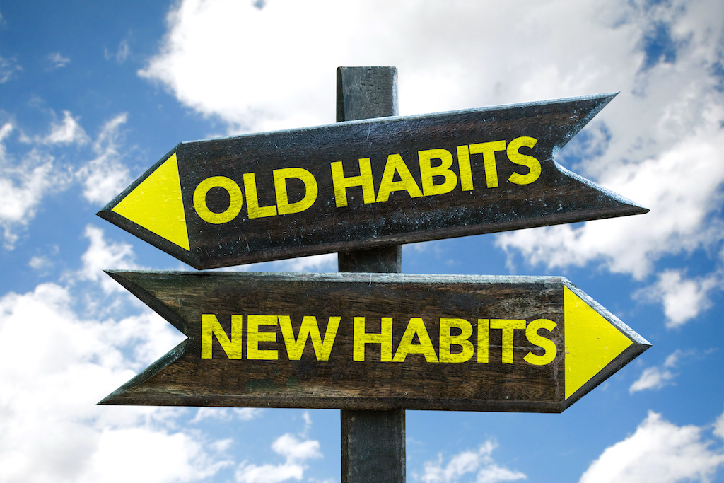 Old Habits – New Habits signpost with sky background