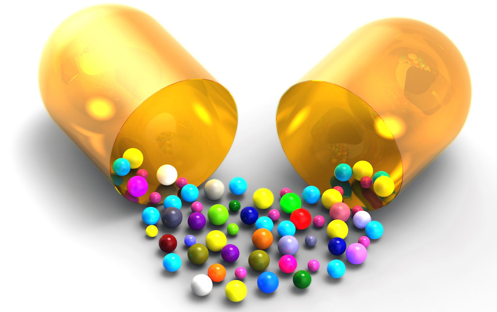 Colored balls spilling from the open medical capsule isolated on