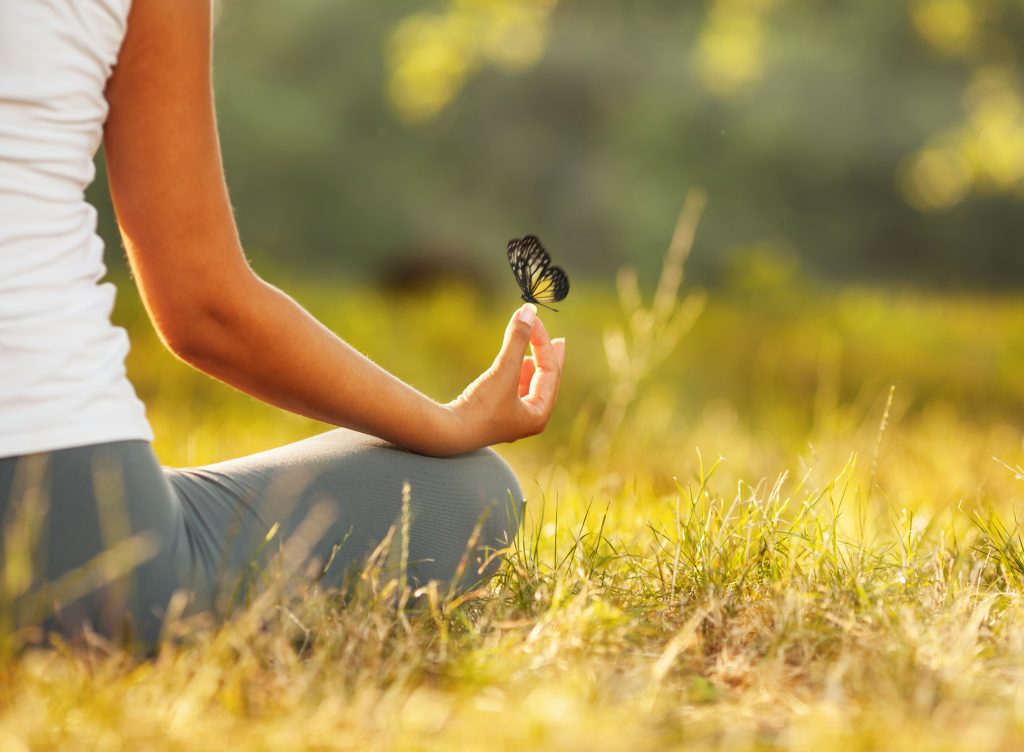 Young woman practicing morning meditation in nature at the park. Health lifestyle concept.